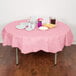 A table with a Classic Pink OctyRound table cover and plates and cups on it.