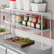 An Avantco stainless steel double deck overshelf with food on it.