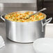 A Vollrath aluminum pot filled with pasta and vegetables on a table.