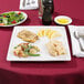 A Libbey white porcelain plate with a piece of bread, salad, and a lemon wedge.