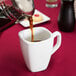 A person pouring coffee into a white Libbey tall porcelain cup.