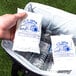 A hand placing a package of Polar Tech Ice Brix cold packs in a cooler filled with water and plastic bottles.