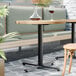 A FLAT Tech black table base with a black pole supporting a table with a glass and wine glass on it.