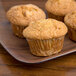 Three muffins on a Carlisle woodgrain rectangular melamine tray.