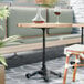A FLAT Tech black restaurant table base with a glass and decanter on top.