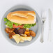 A Creative Converting shimmering silver paper plate with a sandwich, chips, and a fork.