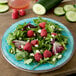 A Carlisle Aqua melamine round plate with a salad and raspberries on it.