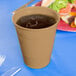 A Creative Converting Glittering Gold plastic cup filled with a cold drink with ice on a table.