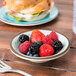 A Carlisle smoke melamine fruit bowl filled with berries on a table.