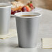 Two Creative Converting shimmering silver paper hot cups filled with a hot beverage on a table.