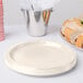 A stack of ivory paper plates with a plate of food next to a bucket of food.