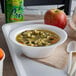 A white Dart foam bowl of soup with noodles and vegetables on a tray.