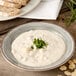 A Carlisle smoke melamine rimmed soup bowl filled with soup and garnished with chives.