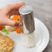 A hand using a stainless steel Ateco round food mold to plate food.