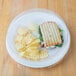 A Dart white foam plate with a sandwich and potato chips on it.