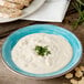 A Carlisle Aqua Melamine rimmed soup bowl filled with soup with chives on top.