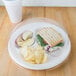 A Dart white foam plate with a sandwich and chips on it.