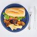 A Creative Converting navy blue paper plate with a sandwich and potato chips on it.