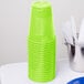 A stack of Fresh Lime Green plastic cups on a table with a white plate.