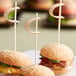 A group of burgers with Tablecraft bamboo picks on a plate.