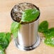 An American Metalcraft stainless steel mint julep cup filled with ice and mint leaves.