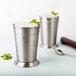 Two Libbey stainless steel mint julep cups with ice and mint in them.