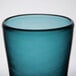 A close up of a teal Carlisle Tritan plastic double rocks glass with a black rim.