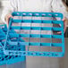 A person using a Carlisle glass rack extender on a blue tray.