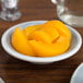 A Carlisle Smoke Melamine fruit bowl filled with peaches on a table.