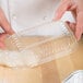 A hand holding a D&W plastic dome lid over a plastic container with dough.