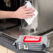 A hand using Urnex Cafe Wipz to clean a coffee machine.