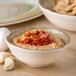 A Carlisle adobe melamine dip bowl filled with hummus and garlic.