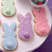 A plate of cookies with bunny shaped frosting next to a Wilton dot pattern embossed cookie.