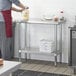 A woman in a kitchen pouring something into a bowl on a Regency stainless steel work table.