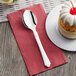 A white plate with a Visions white heavy weight plastic spoon and a slice of cake.