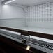 A black Turbo Air air curtain merchandiser with a glass door and a light on a shelf.