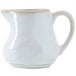 A white Tuxton China creamer with a handle.