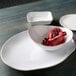A close-up of a white Tuxton Artisan china ellipse plate with a pomegranate on it.