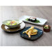 A rectangular china tray with sushi, fried food, and salad on a table.