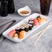 A Tuxton rectangular china tray with sushi and chopsticks on it.