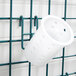 A white plastic cup hanging from a green wire rack.