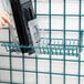 A hand placing a plastic container in a black and clear Metro SmartWall G3 rack.