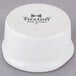 A white Tuxton china ramekin with black Tuxton logo.