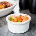 A Tuxton China ramekin filled with salsa on a table.