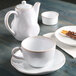 A white Tuxton china teapot and cup on a table.