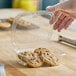A clear plastic tamper-resistant hinged container with a flat lid, holding several chocolate chip cookies.
