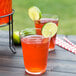 A customizable Arcoroc beer glass filled with orange liquid and a lime wedge.