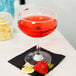 A glass of red margarita with strawberries and lemons.