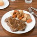 A Chef & Sommelier white bone china plate with meat and vegetables on it.