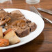 A Chef & Sommelier white bone china plate with meat and vegetables, a fork and knife.